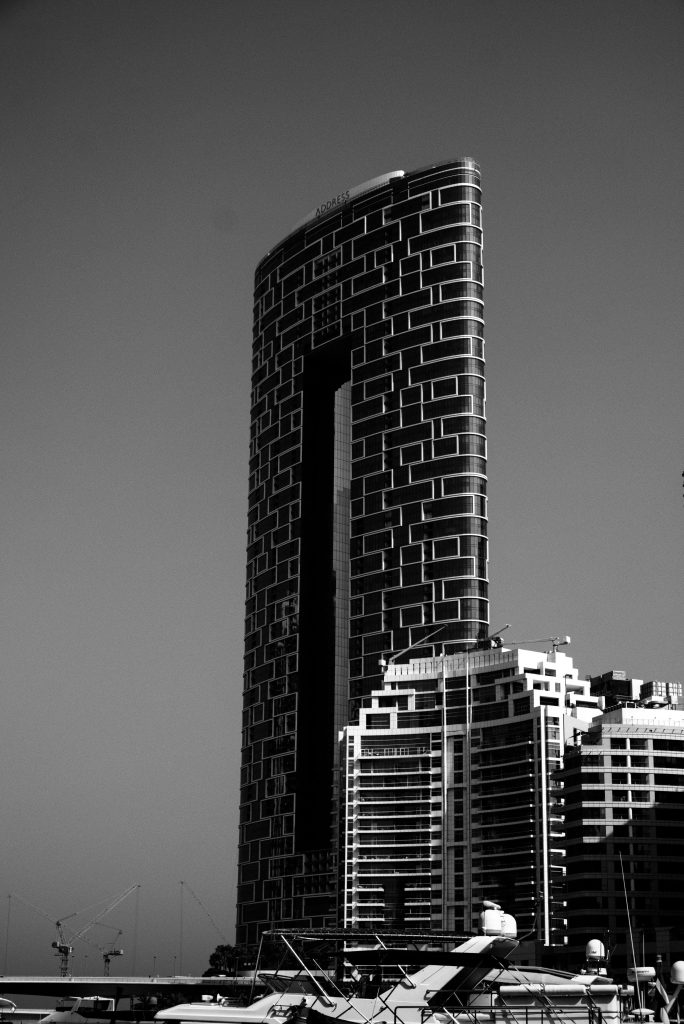 Iconic skyscraper with geometric facade in Dubai Marina, captured in black and white.